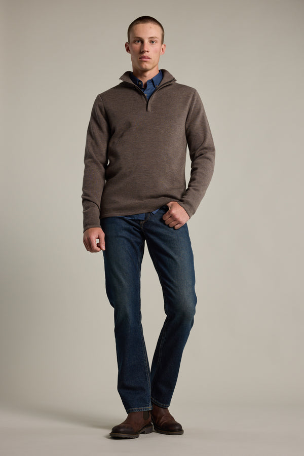 A person stands against a plain background wearing the Barkers Brandon ZQRX Merino 1/4 Zip pullover, blue collared shirt, blue jeans, and brown shoes with one hand in their pocket—ideal for cold-weather layering.