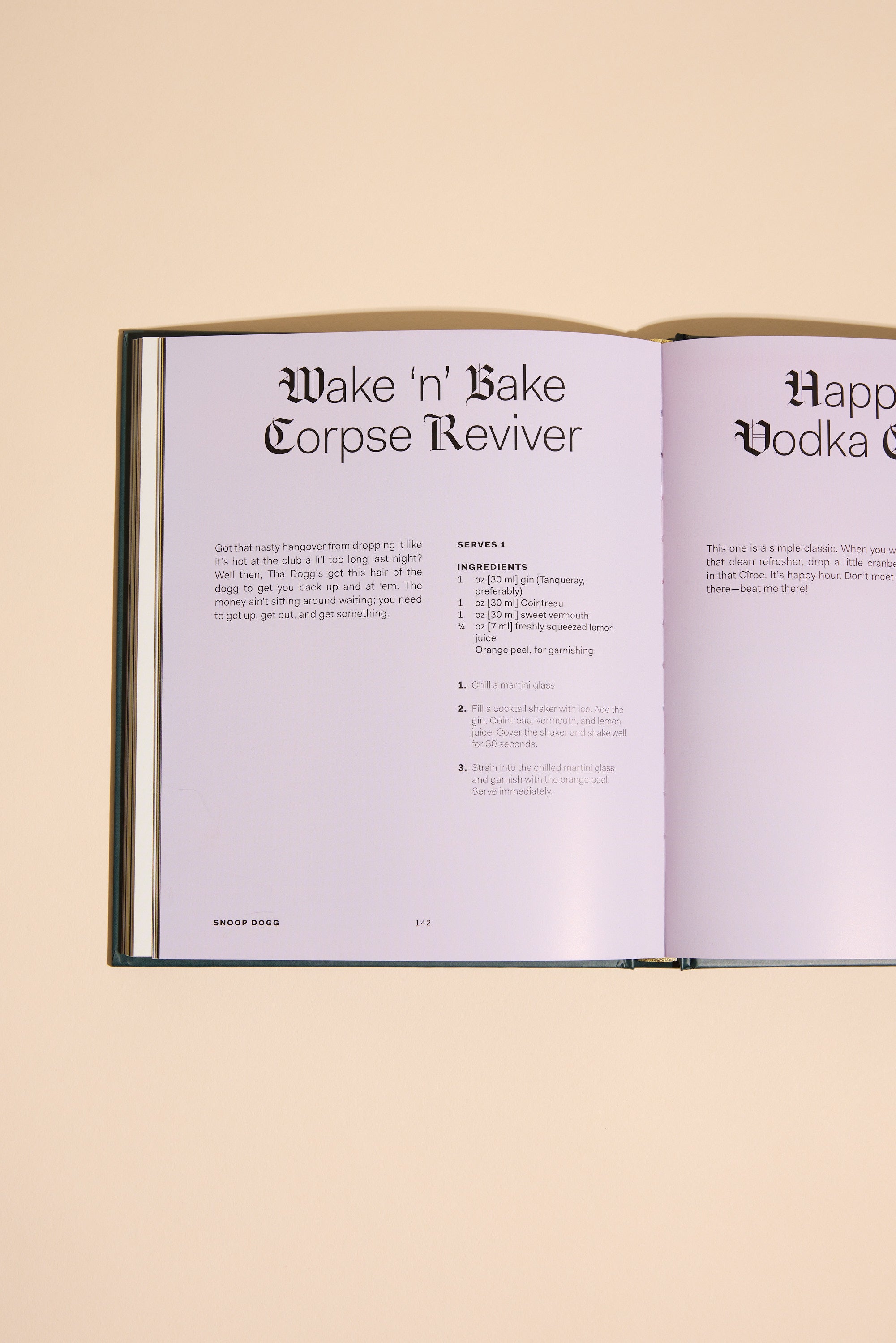An open copy of From Crook to Cook by Other rests on a beige surface, displaying the Wake n Bake Corpse Reviver recipe with ingredients and instructions on a light purple background.