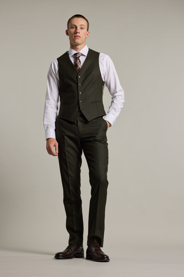 A man stands against a light background wearing Barkers Howard Suit Trousers crafted from Super 100s wool, paired with a dark three-piece suit, white dress shirt, patterned tie, and dress shoes. His hands are at his sides and his expression is neutral.