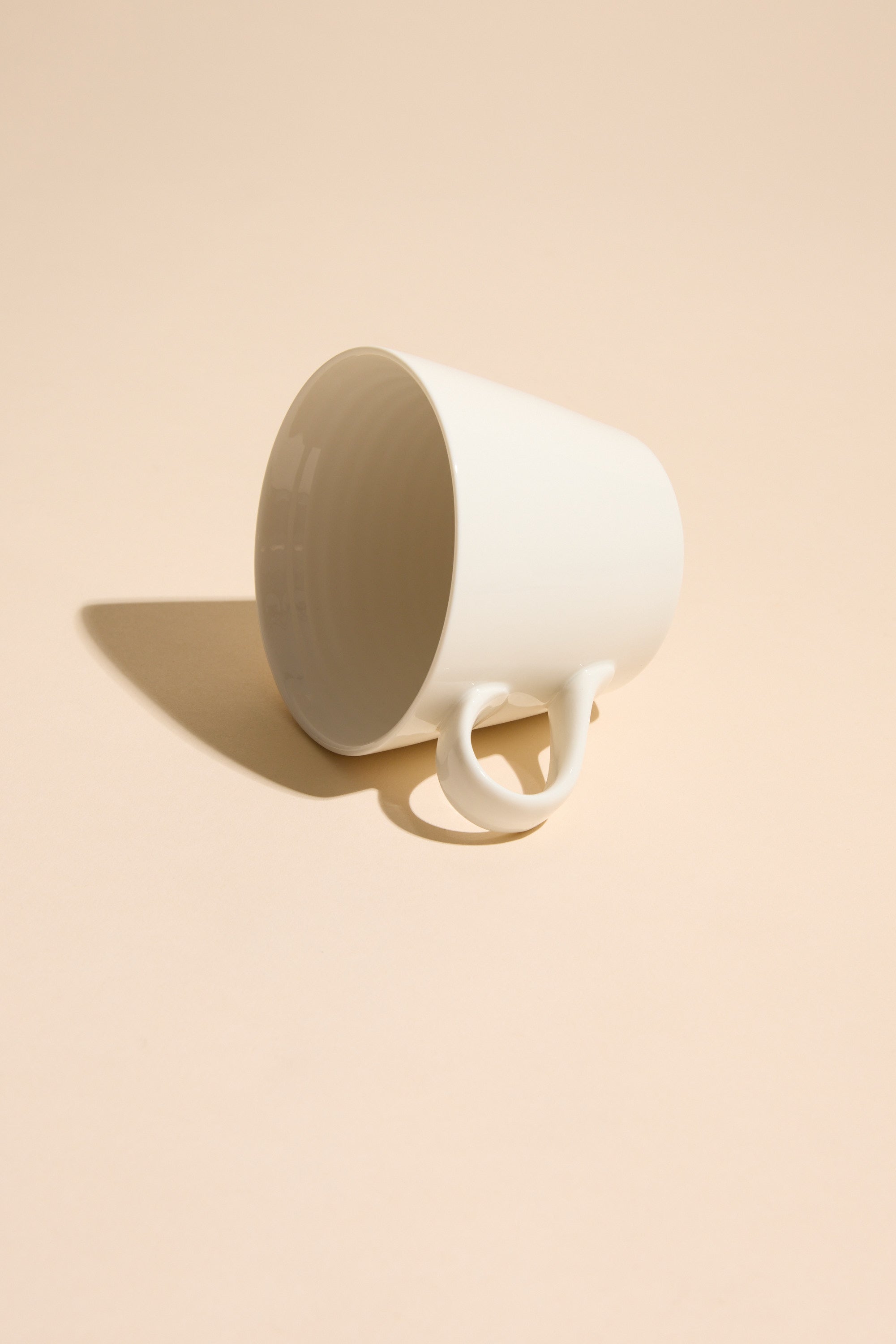 A Bucket Mug - Old Fart by Other rests on its side atop a light beige surface, casting a soft shadow—making it the perfect quirky gift for friends who enjoy unique ceramics.