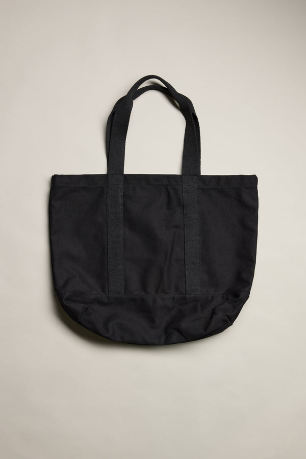The Barkers Supply Co. Canvas Tote Bag by Barkers, made from durable black canvas with two handles, lies flat on a neutral light background.