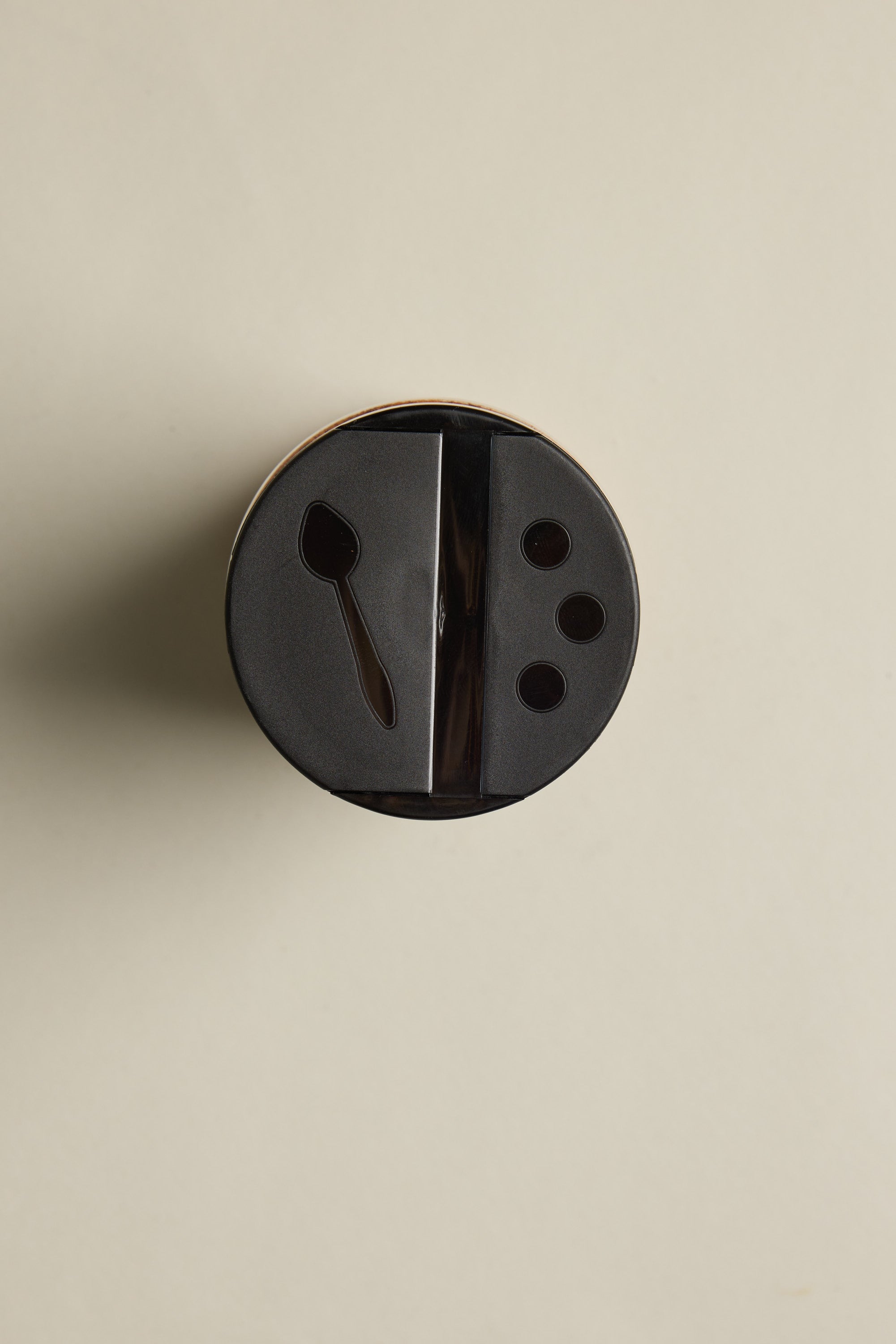 A 300g jar of The Lamb Rub from Other, featuring a black plastic lid with a spoon-shaped opening and three circular holes, is displayed on a plain beige background—ideal for gluten-free recipes.