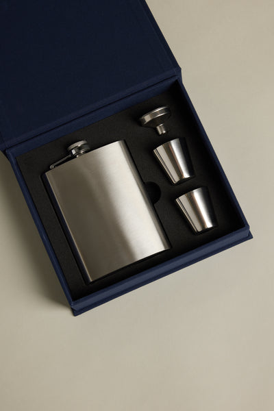 The Barkers "The Essentials Hip Flask" kit comes in a blue gift box with a stainless steel flask, two shot glasses, and a funnel—all securely set in black foam cutouts.