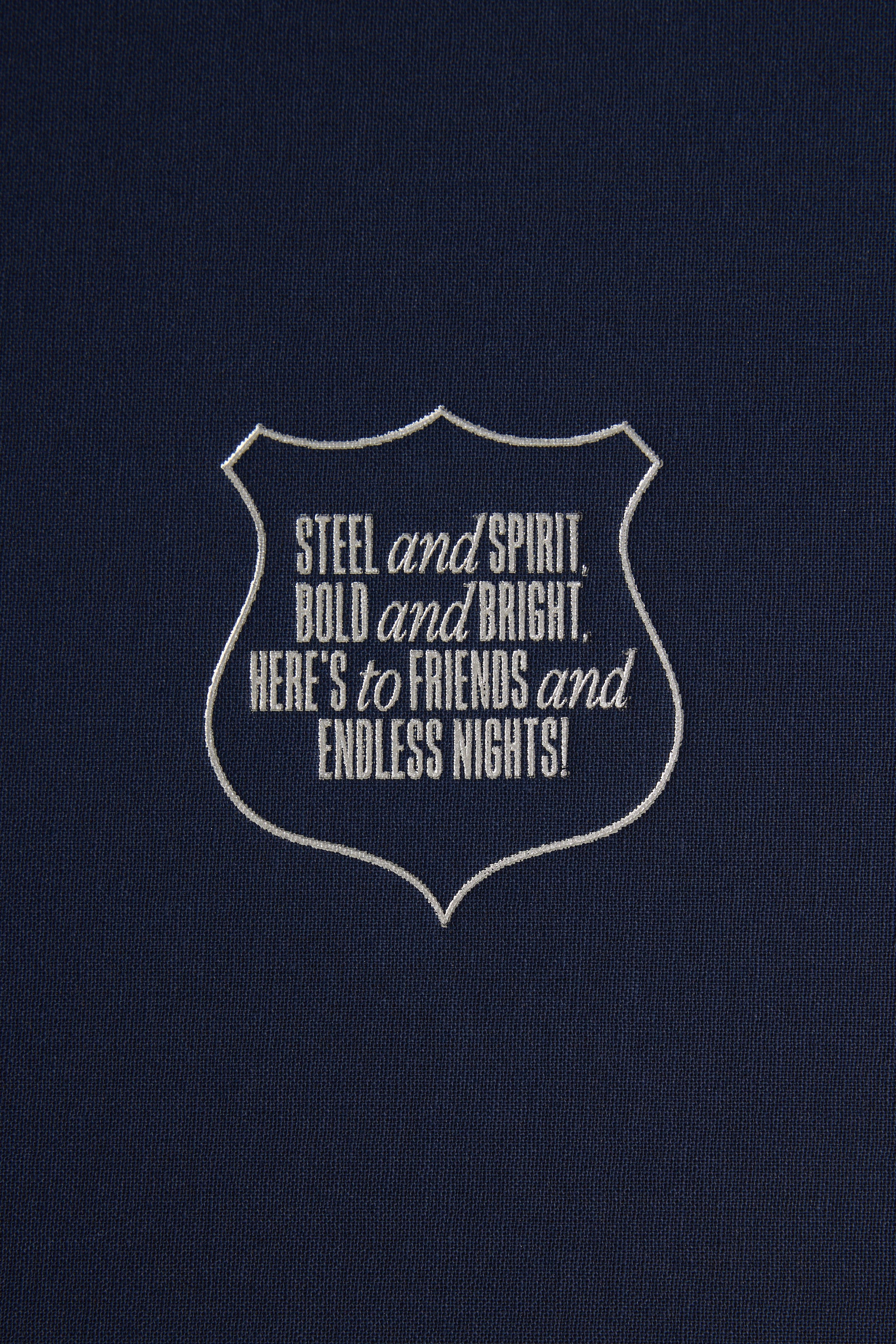 A dark blue background with a white outlined badge reads: STEEL and SPIRIT, BOLD and BRIGHT, HERE’S to FRIENDS and ENDLESS NIGHTS!—the perfect toast for Barkers’ The Essentials Hip Flask gift box.