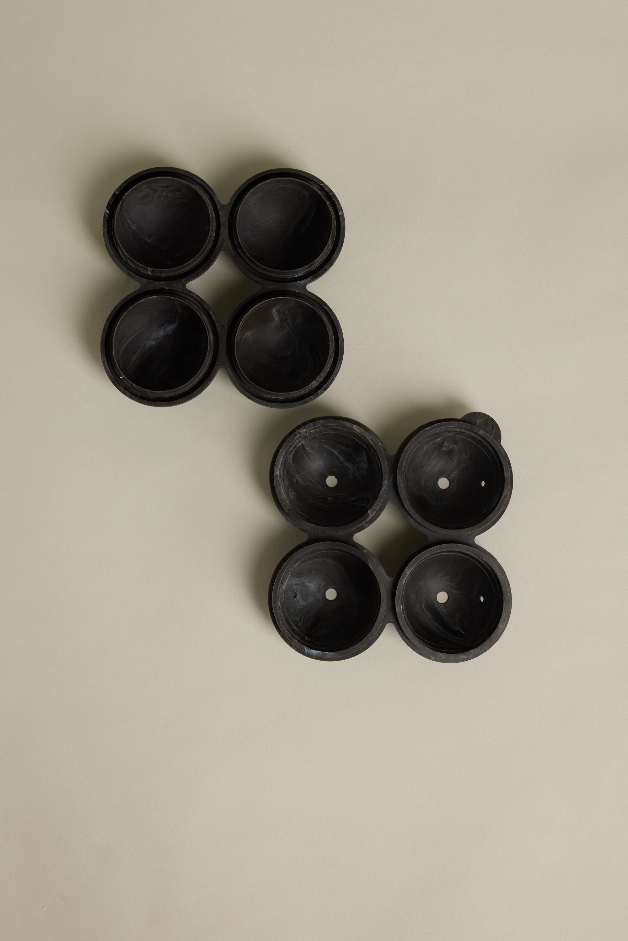 Four Barkers Ice Tray Sphere Marble Black molds are at the top left, with another four arranged diagonally below. Each set resembles large round cocktail ice spheres, all displayed on a plain beige background.