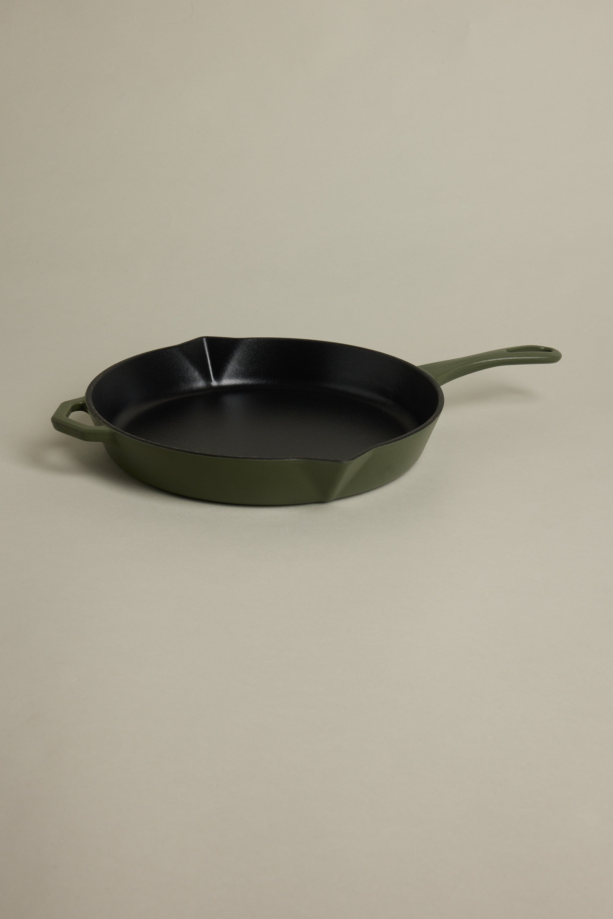 The IronClad Satin Enamel Cast Iron - 28cm Legacy Pan satin, featuring a green finish, handle and helper handle, sits on a beige surface. Its black interior is induction-ready and ideal for non-stick cooking.