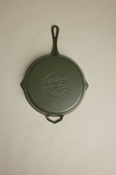 The IronClad Satin Enamel Cast Iron - 28cm Legacy Pan satin is shown handle up on a neutral, light background, with the brand’s name embossed on the green enamelled base.