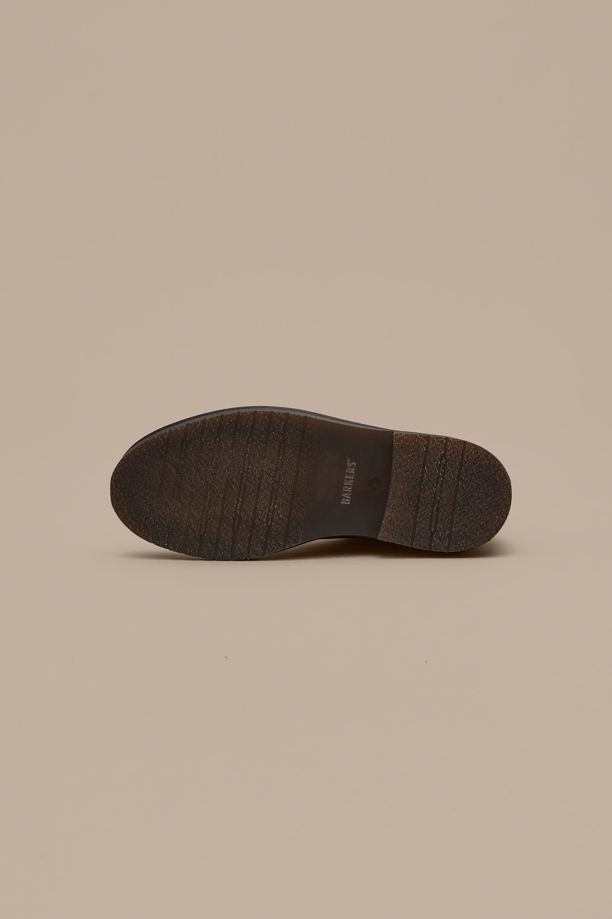 The Barkers Howarth Desert Boot is displayed upside down, highlighting its textured sole against a beige background—a subtle nod to classic Portuguese footwear craftsmanship.