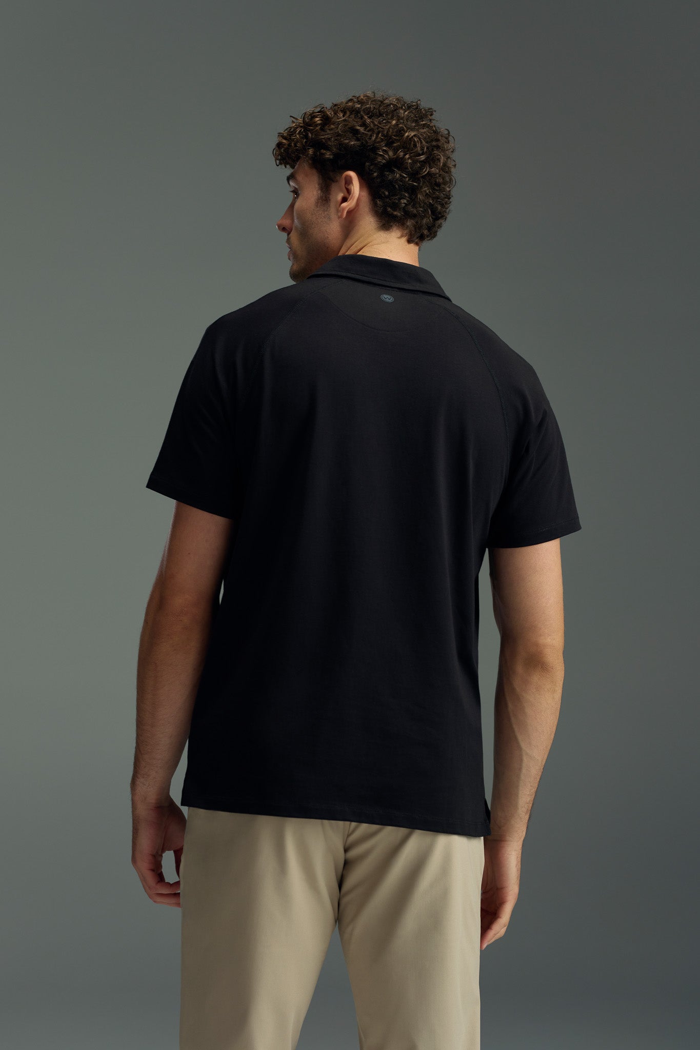 A man in a black WearEver Outbound Polo, made from lightweight, stretchy, and breathable cotton-blend fabric.