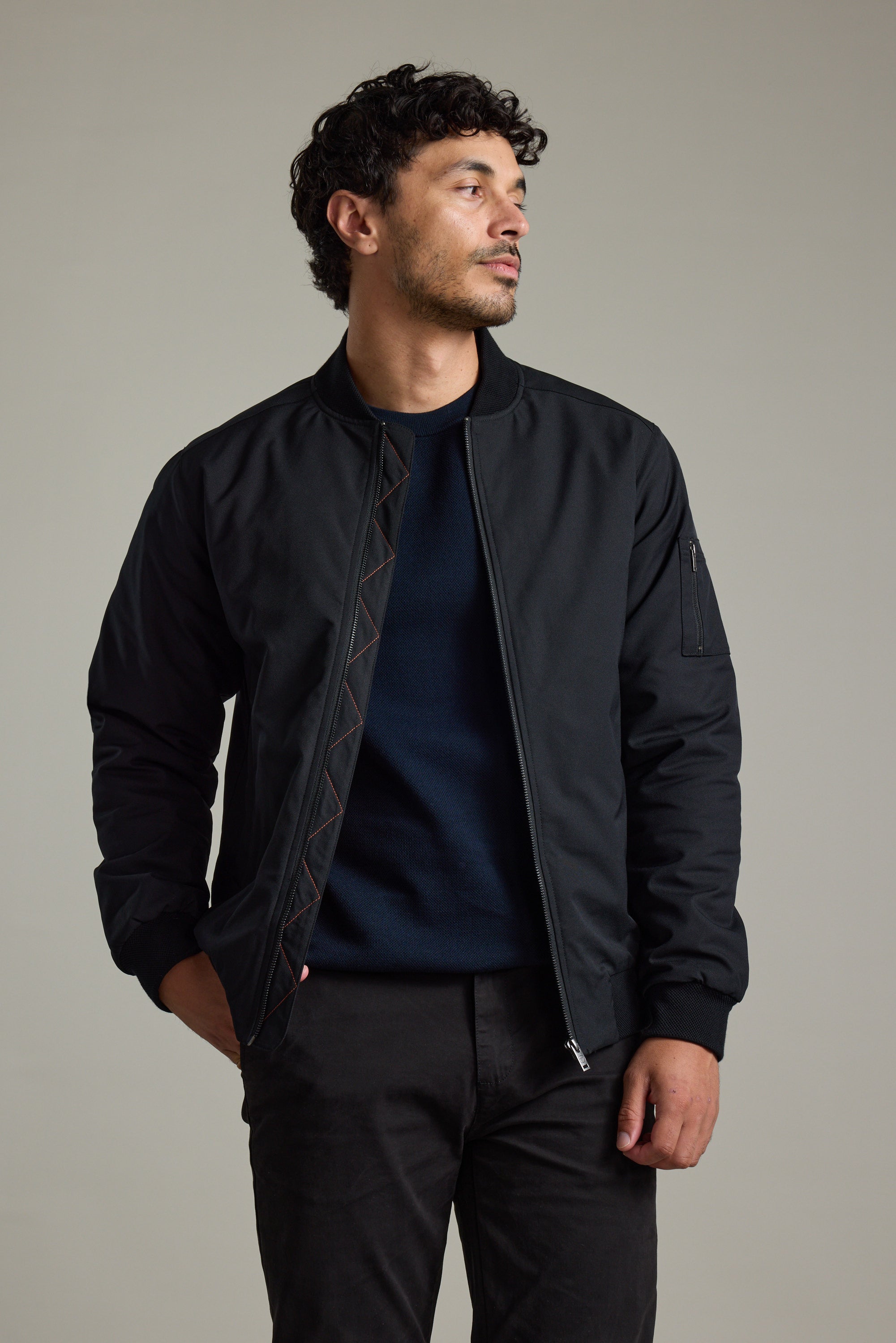 Man in Barkers Dunhill Bomber Jacket and dark pants, standing with one hand in pocket.