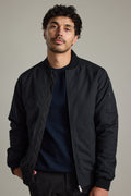 Man with short curly hair wears a Barkers Dunhill Bomber Jacket and navy shirt against a plain background.