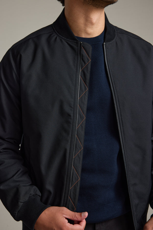 Man in Barkers Dunhill Bomber Jacket unzipping it with his right hand.