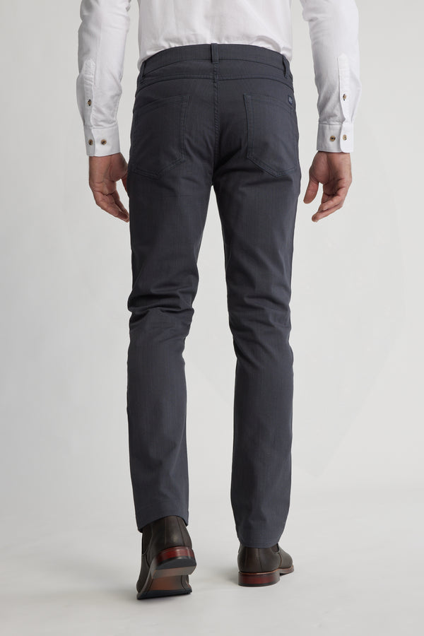 A person wearing a white dress shirt and Barkers Oxmor 5 Pkt Pant O in dark gray with black dress shoes is shown from the back, standing against a plain light-colored background to highlight the pants’ rear view.