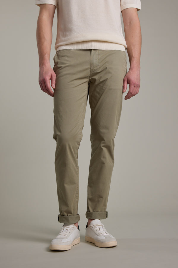 A person models Barkers Kingly Chino Pant in light khaki, paired with a white short-sleeve shirt and sneakers. The image, cropped at the shoulders, focuses on the lower half of the body against a plain background.