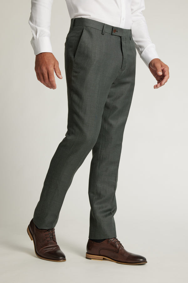 A person wears Barkers Inverness Suit Trouser in dark grey with a white dress shirt and brown leather shoes, standing against a plain light background; the outfit is formal and neatly tailored.