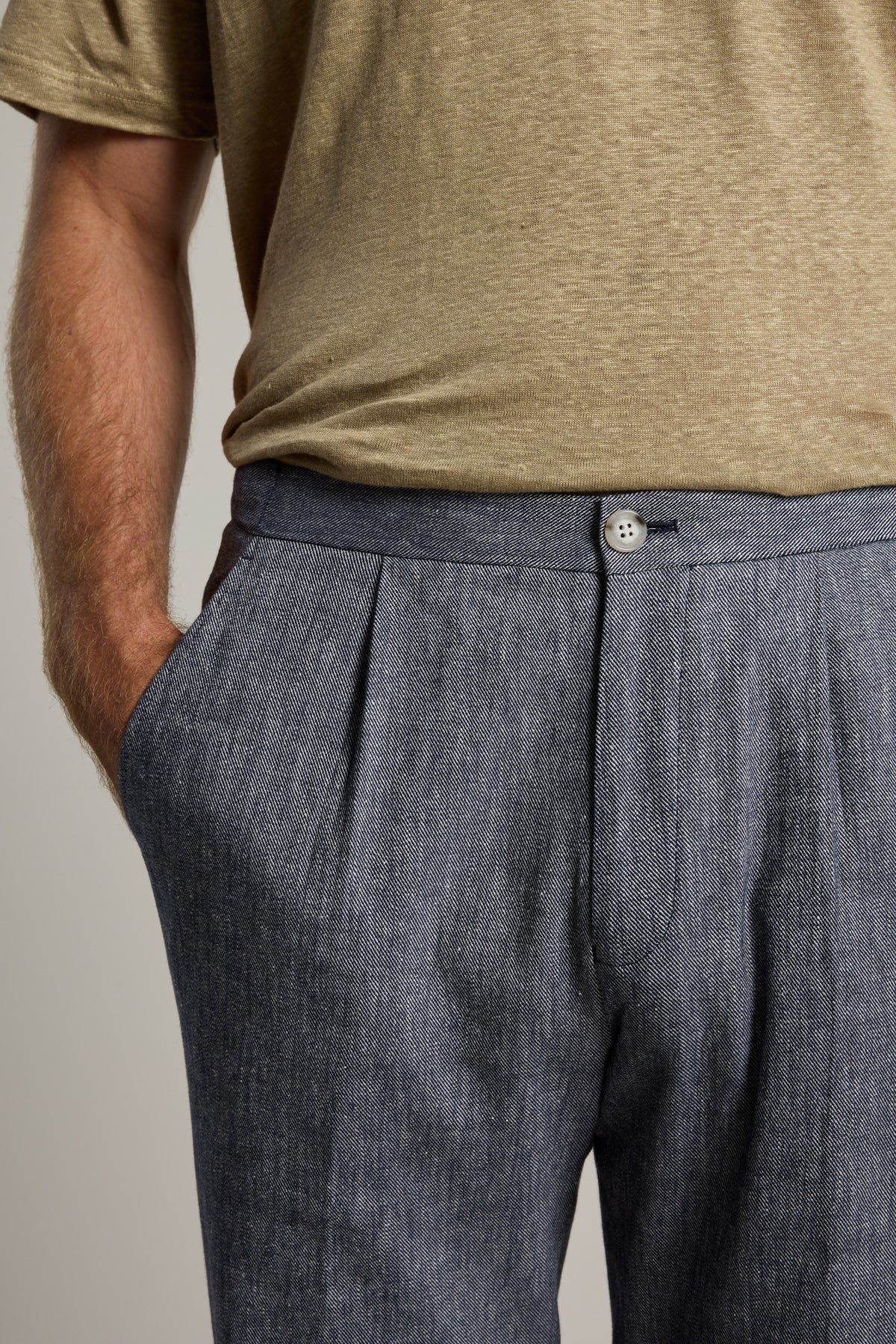 Wearing Barkers Paden Twill Pant in grey and a beige t-shirt, one hand in pocket.