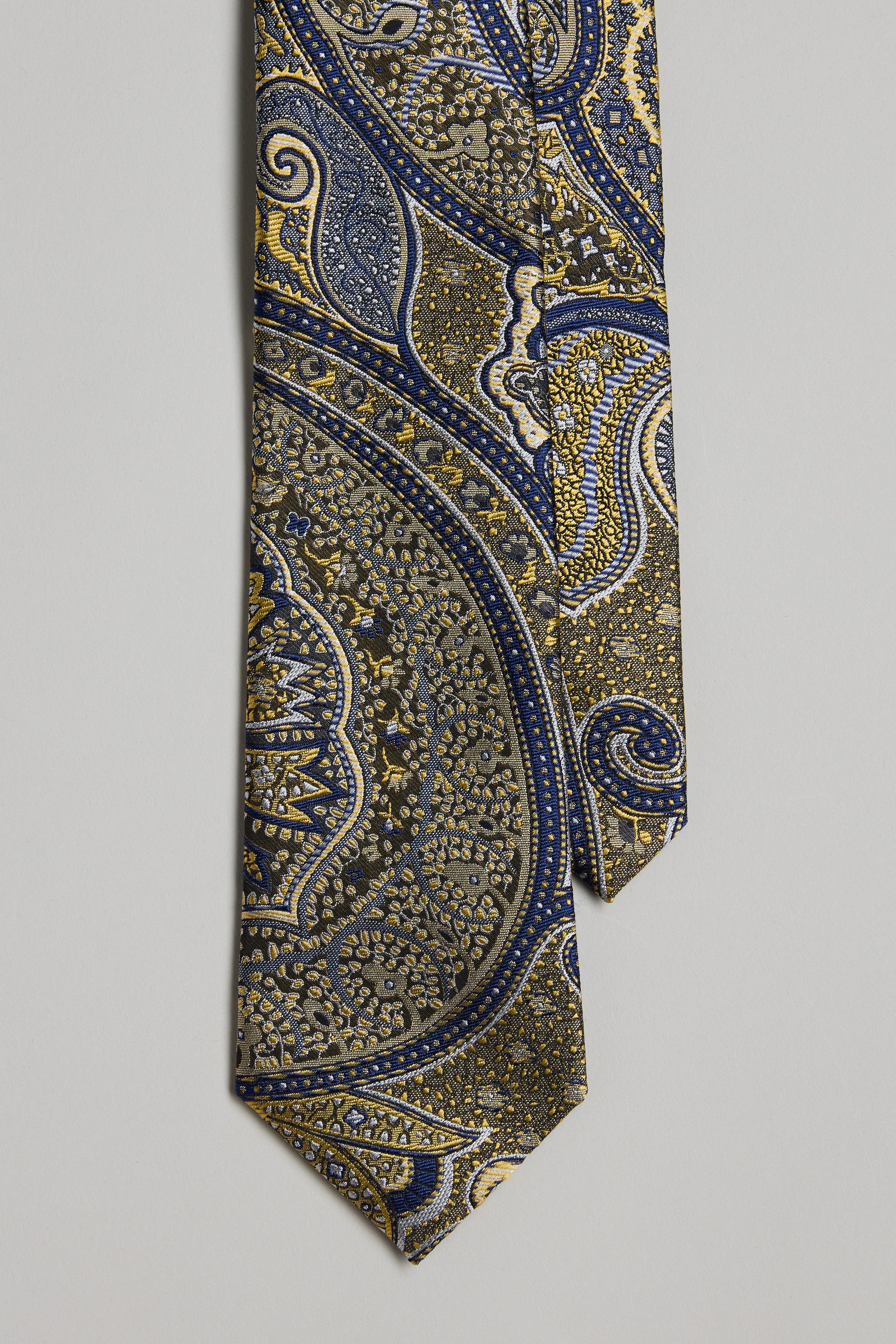 The Shubert Paisley Tie by Barkers showcases an intricate paisley pattern in gold, blue, and navy on a neutral silk background—ideal for pairing with Barkers silk bow ties and pocket squares at formal events.