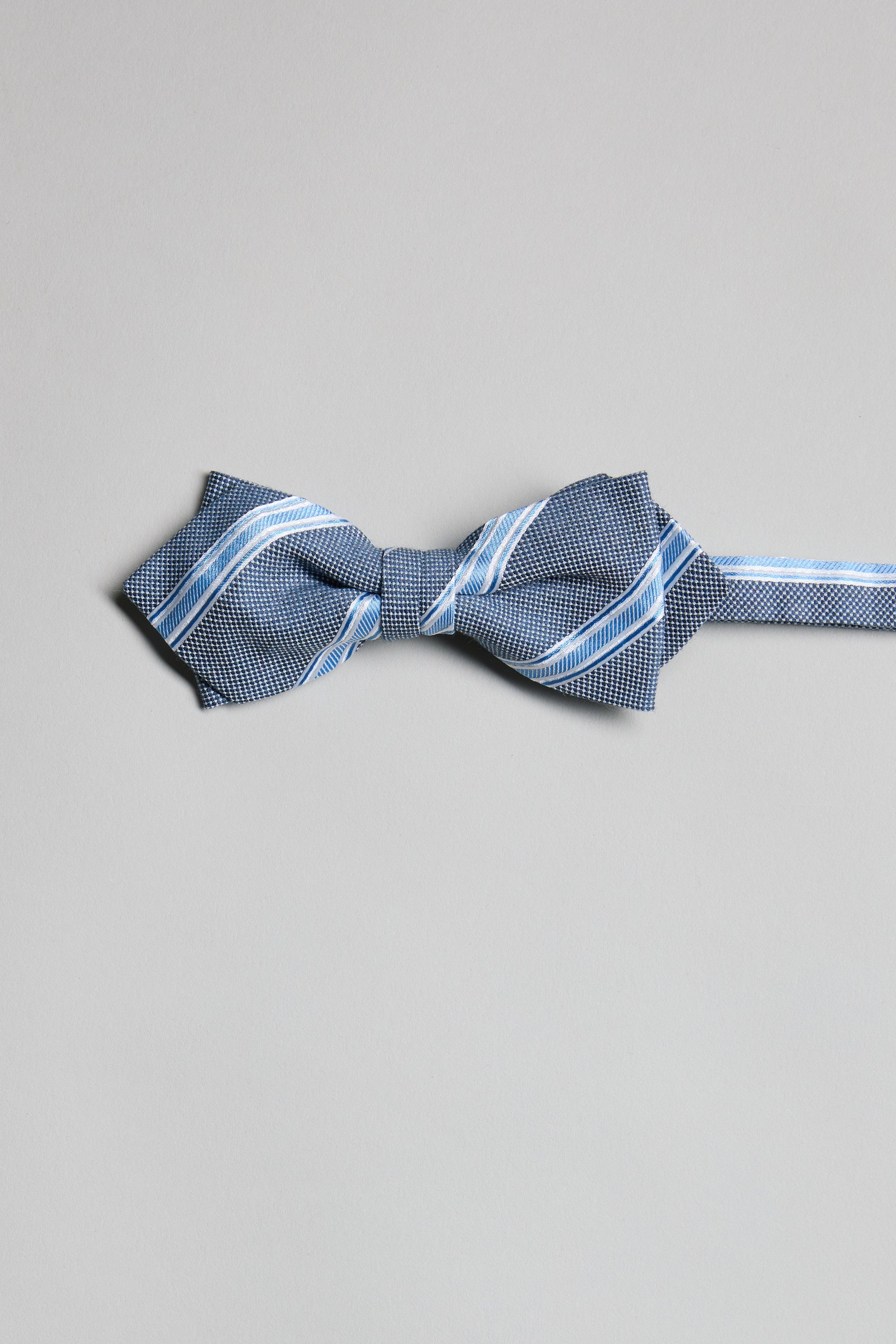 The Parisian Stripe Bow Tie by Parisian is shown in blue and white on a light grey surface with its strap extended. Handmade in New Zealand, this elegant accessory brings refined charm to any formal ensemble.