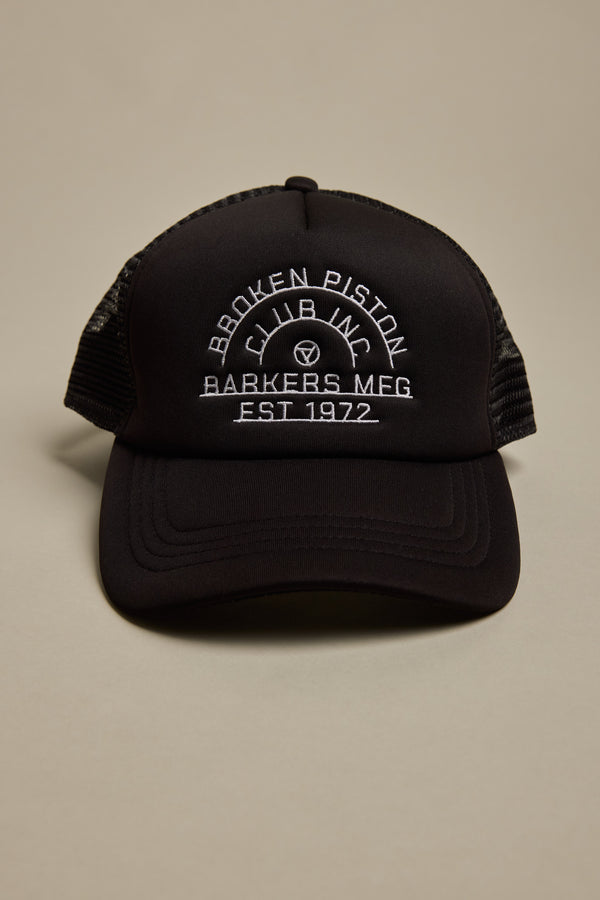 The Barkers Piston Club Trucker Cap is a black cap with mesh sides, an adjustable fit, and a front white embroidered logo that reads: BROKEN PISTON CLUB INC, BARKERS MFG, EST 1972 in curved and straight lines.
