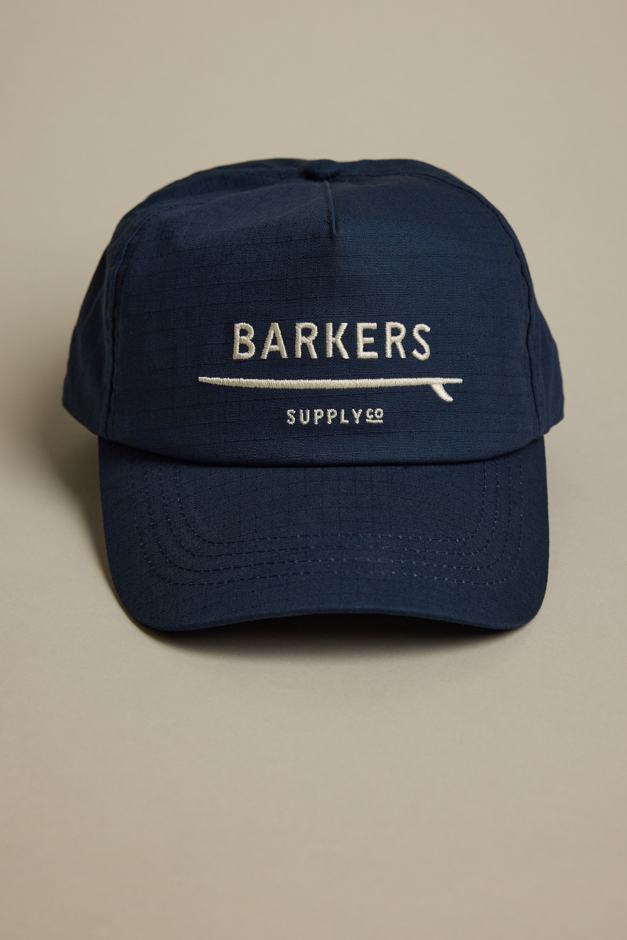 The Barkers Wave Master Cap in navy features BARKERS and SUPPLY CO embroidered in white on the front, an adjustable snapback closure, and is shown against a plain light background.