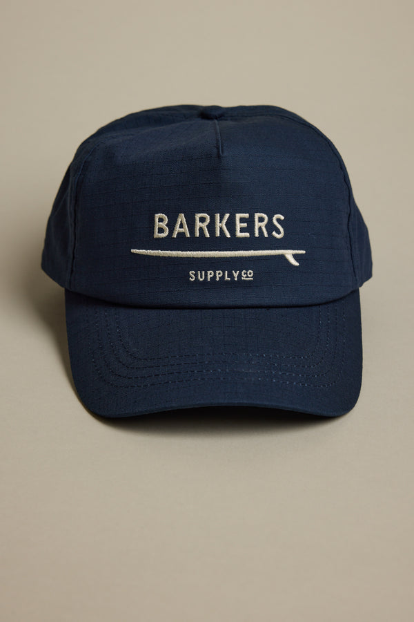 The Barkers Wave Master Cap in navy features BARKERS and SUPPLY CO embroidered in white on the front, an adjustable snapback closure, and is shown against a plain light background.