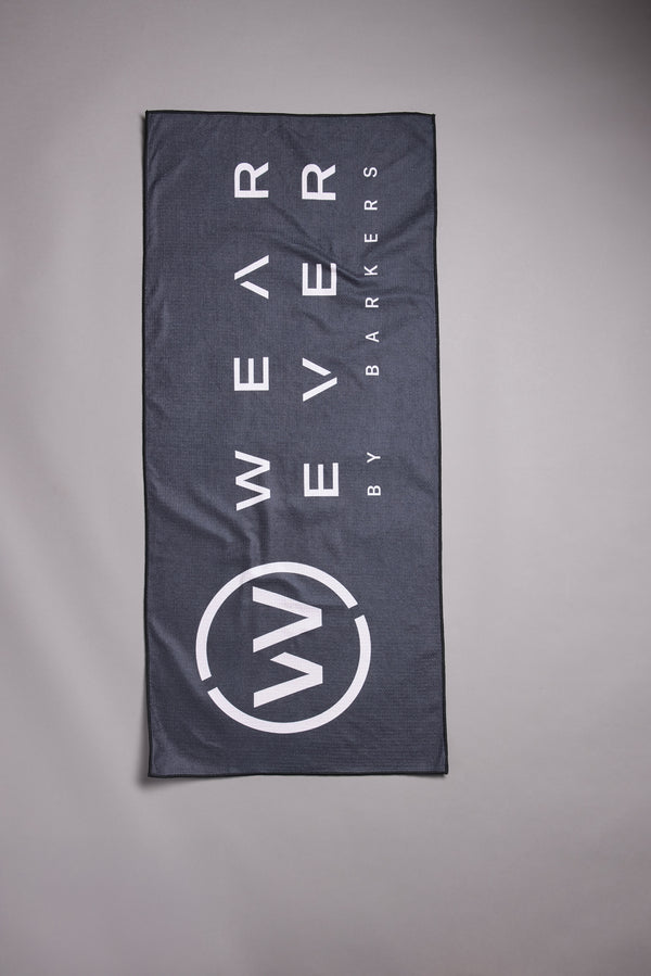 The WearEver Utility Towel by WearEver is a rectangular, dark grey microfibre towel featuring bold white "WEAR EVER BY BARKERS" text and a circular W logo near the bottom, displayed flat on a light grey background.