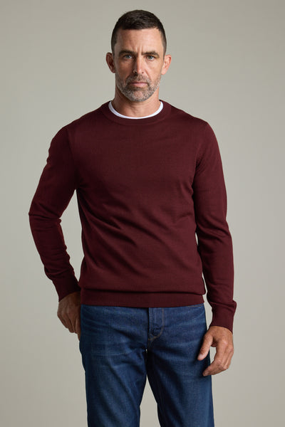 Man in a Barkers Skyland ZQrx Merino Crew sweater and jeans stands against a plain background.