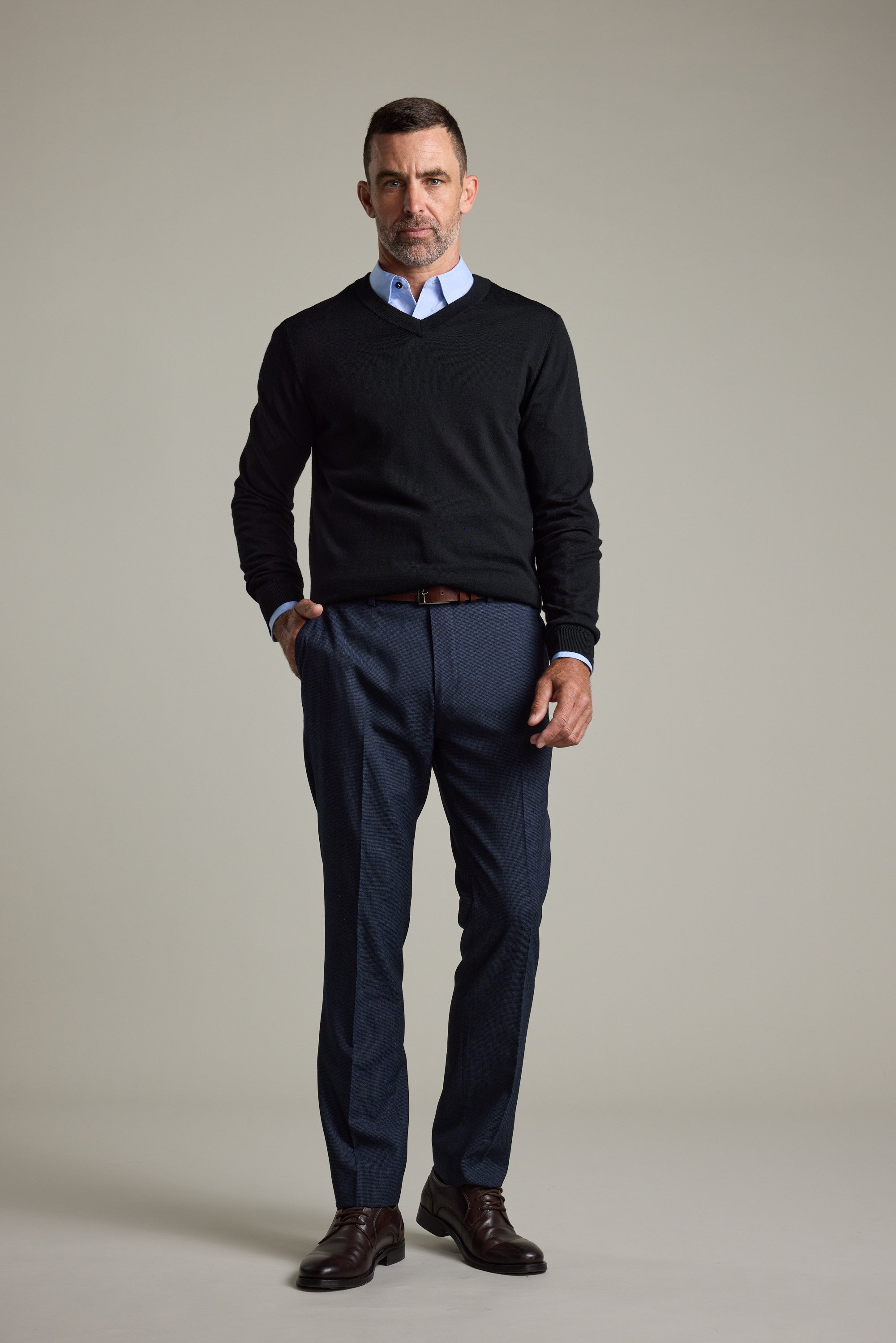 Man in a black Barkers Skyland ZQrx Merino Vee sweater, blue shirt, and dress pants.