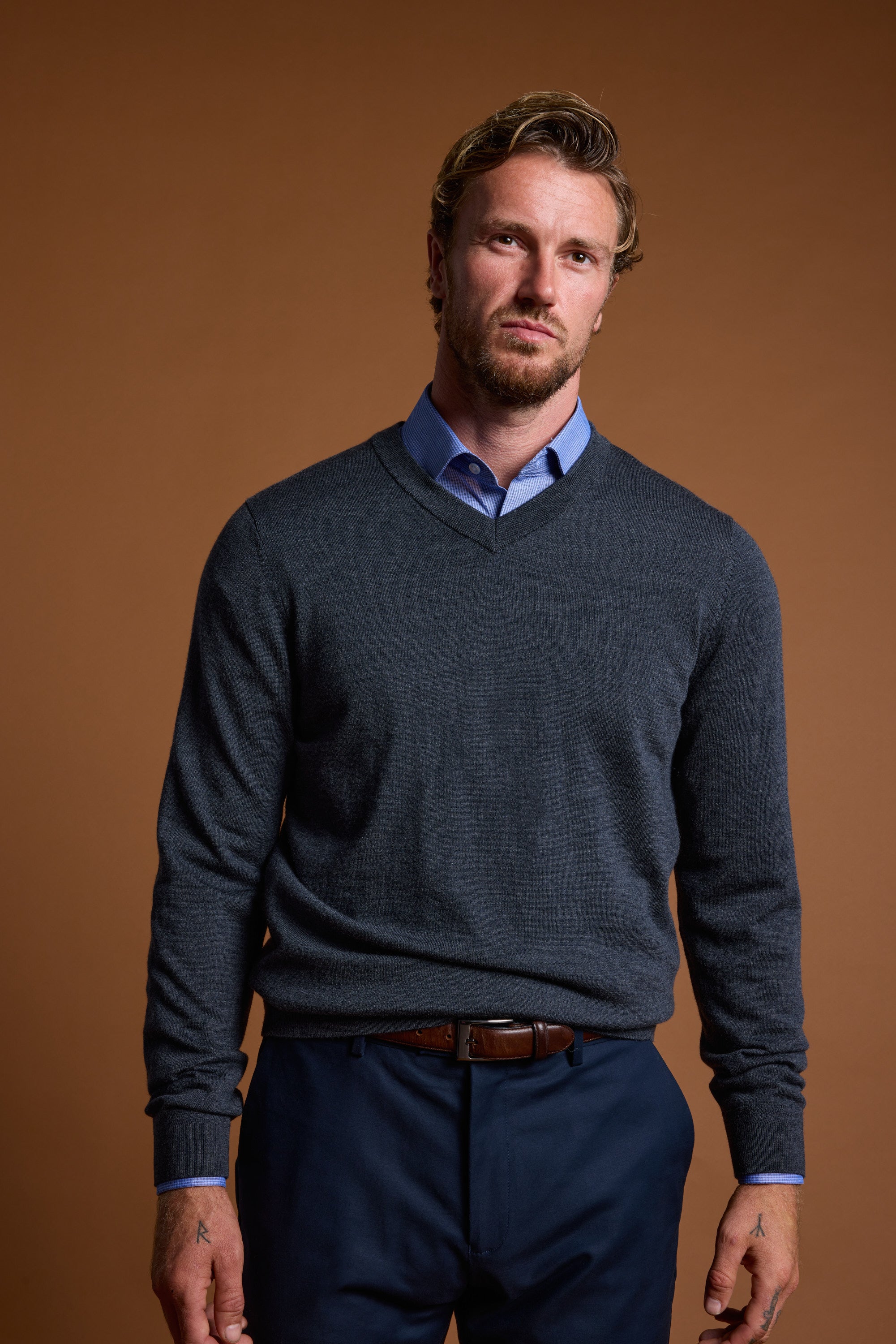 A man in a Barkers Skyland ZQrx Merino Vee sweater stands against a plain brown background.