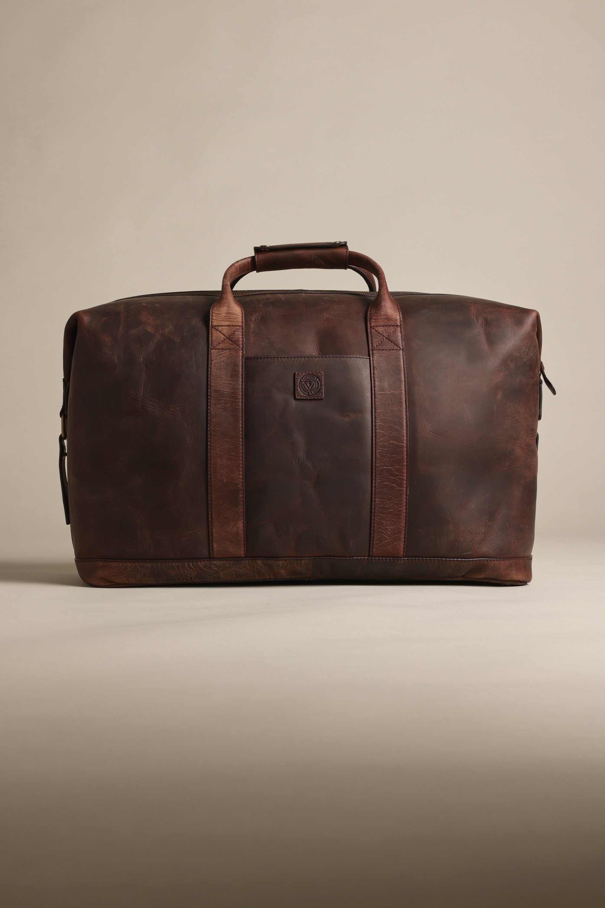 The Barkers Costello Leather Weekender is a spacious, dark brown bag with two handles and a front logo, shown on a beige background—ideal for those seeking premium leather luggage.