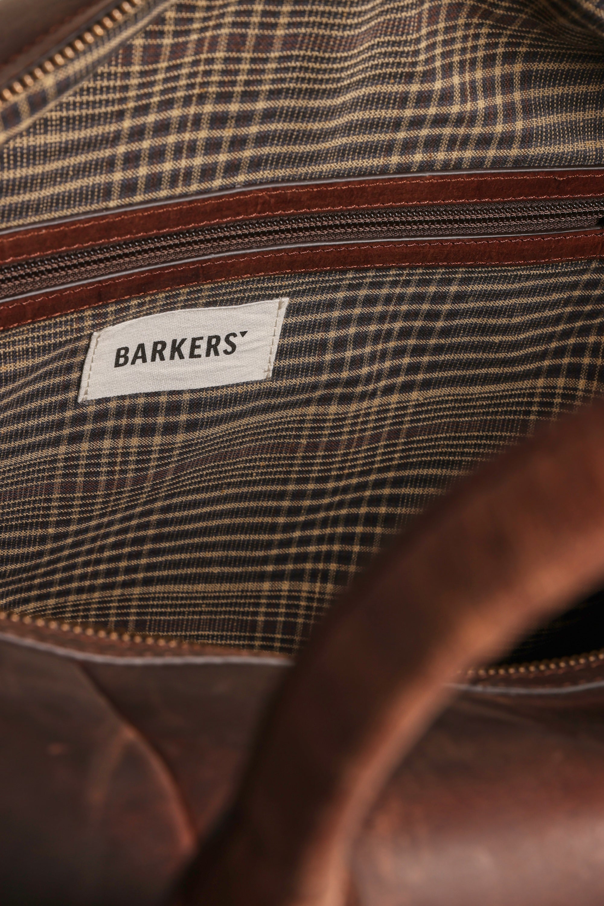 Close-up of the Costello Leather Weekender by Barkers, featuring a striped fabric lining, brown zipper, and a white Barkers label sewn inside.