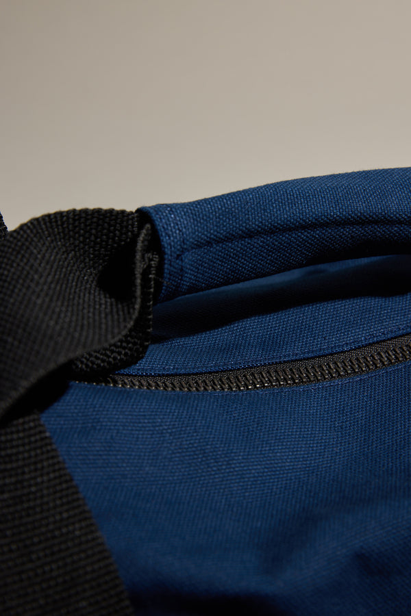 Close-up of the Barkers Canvas Duffle Bag in blue cotton canvas with a black strap and visible stitching, highlighting its textured fabric and opening—an ideal travel companion from Barkers.