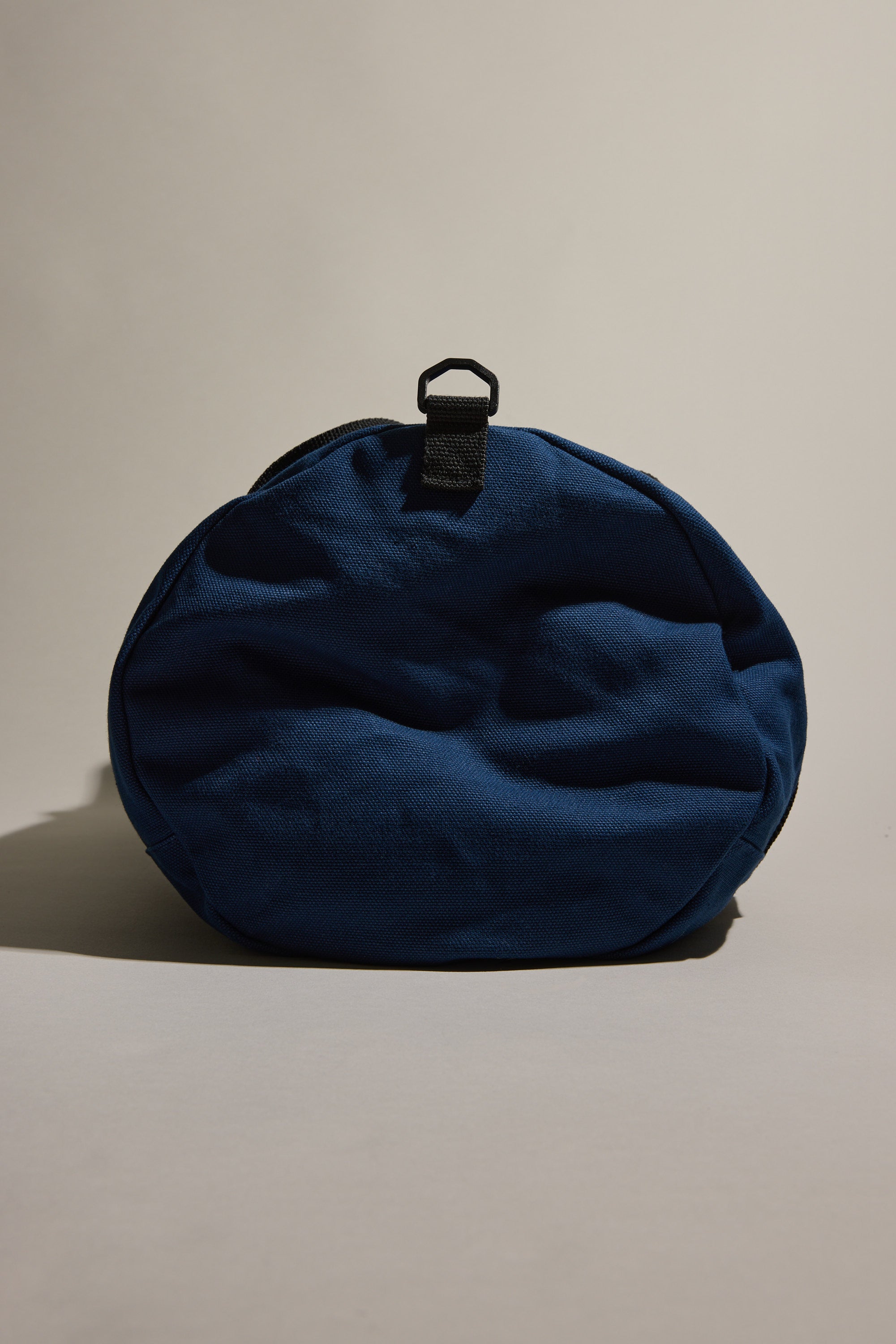 The Barkers Canvas Duffle Bag, round and blue with a black top strap, stands upright against a neutral background—your ideal travel companion from Barkers.