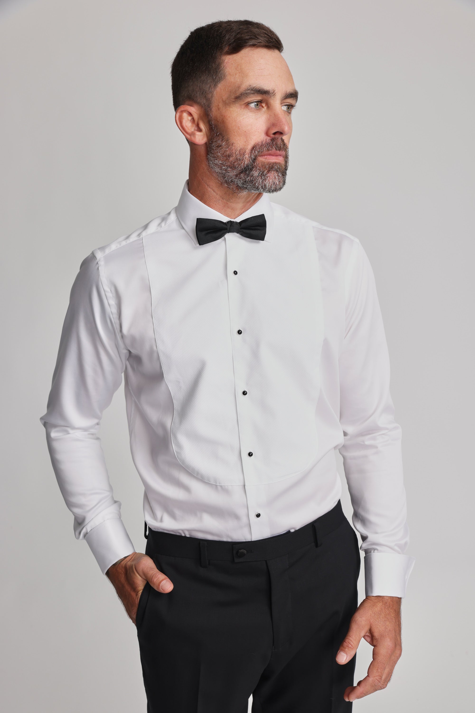 Man in Barkers Eldridge Dress Shirt, black bow tie, tuxedo bib, looking to the side.