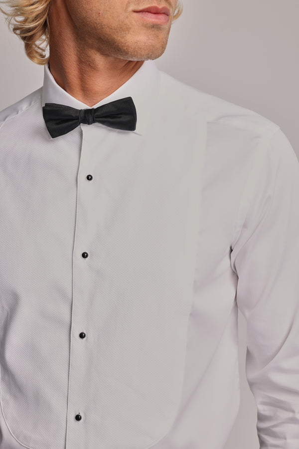 A man wears the Barkers Eldridge Dress Shirt, featuring a tuxedo bib and black buttons, paired with a black bow tie. His face is partially visible, highlighting the classic shirt and bow tie combination.