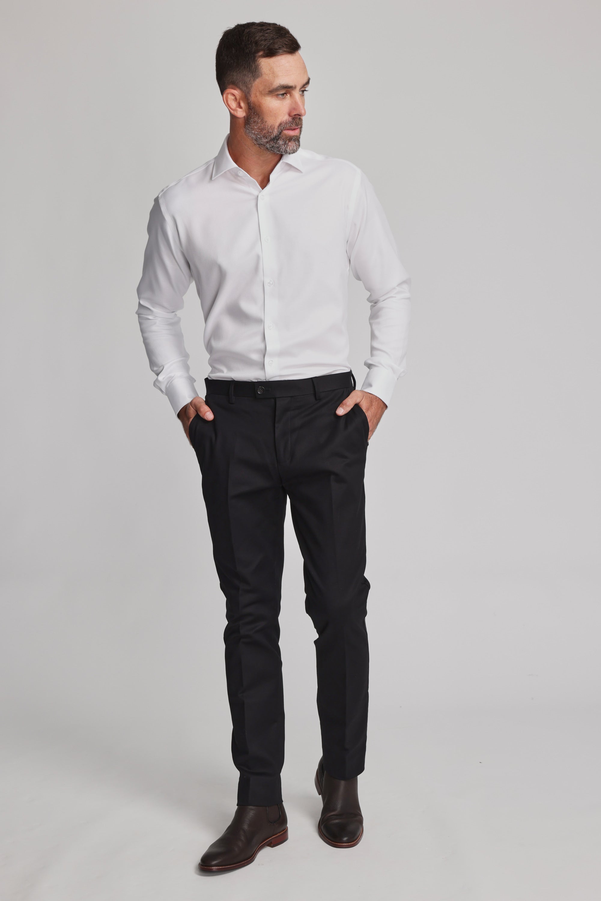 A man with short dark hair and a beard wears the Barkers Mexted Texture Shirt, black dress pants, and dark brown shoes. He stands with hands in his pockets, looking to the side against a plain light background.