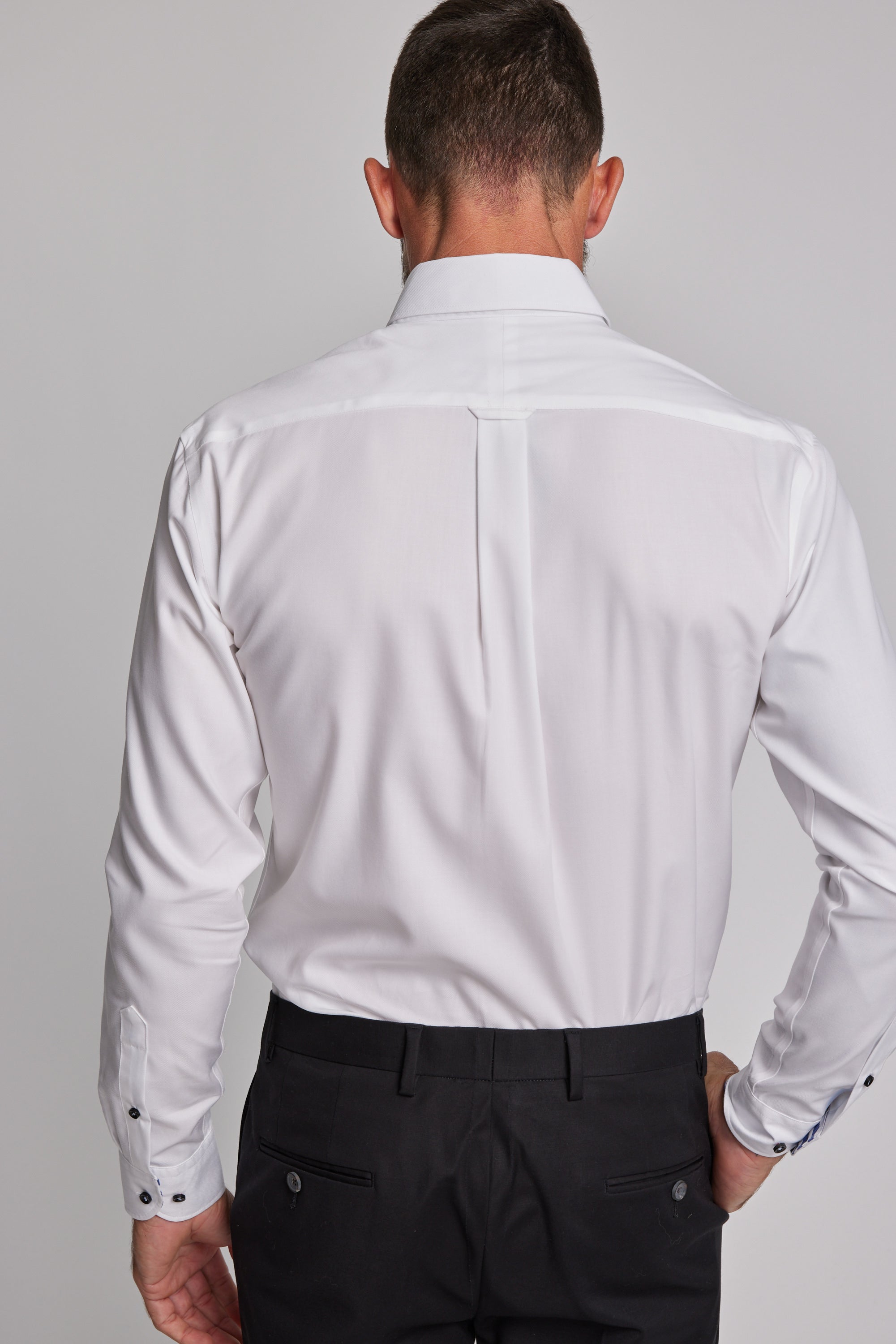 A man is shown from the back wearing the Barkers Verona Shirt, a tailored fit, long sleeve 100% cotton business shirt, paired with black pants against a plain light gray background.