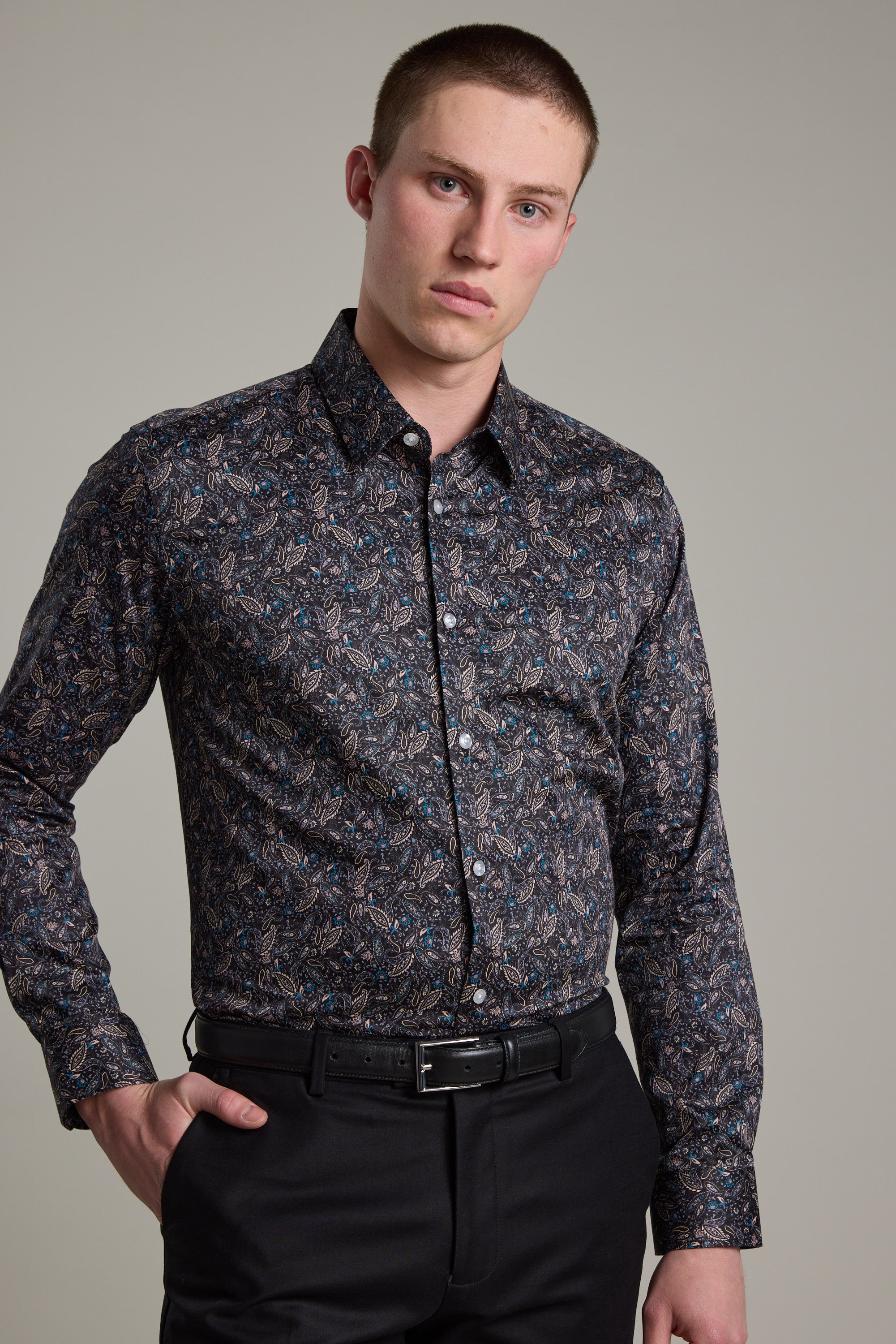 A young man with short hair wears the Barkers Hilton Print Shirt paired with black pants, standing against a plain light background, one hand on his hip.