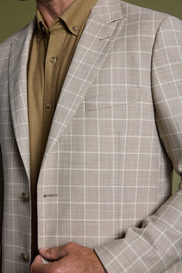 A man adjusts his Barkers Prestwick Check Blazer, a light beige checkered jacket, worn over a tan button-up shirt, shown from chest to chin.