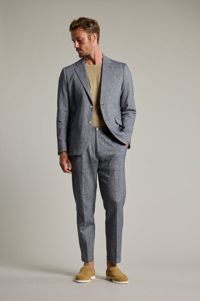 Man wearing Barkers Paden Twill Pant with beige shirt and grey summer suit, looking down.