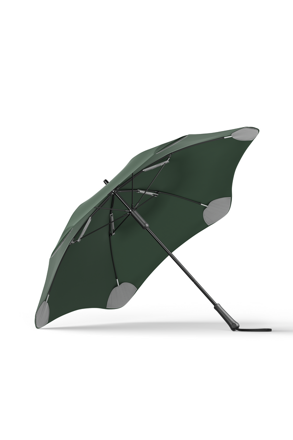 The Blunt Classic Umbrella by Blunt, in dark green with reinforced gray patches and black ribs, is shown open and leaning on its side against a white background, offering superior rain protection as a reliable full-length umbrella.