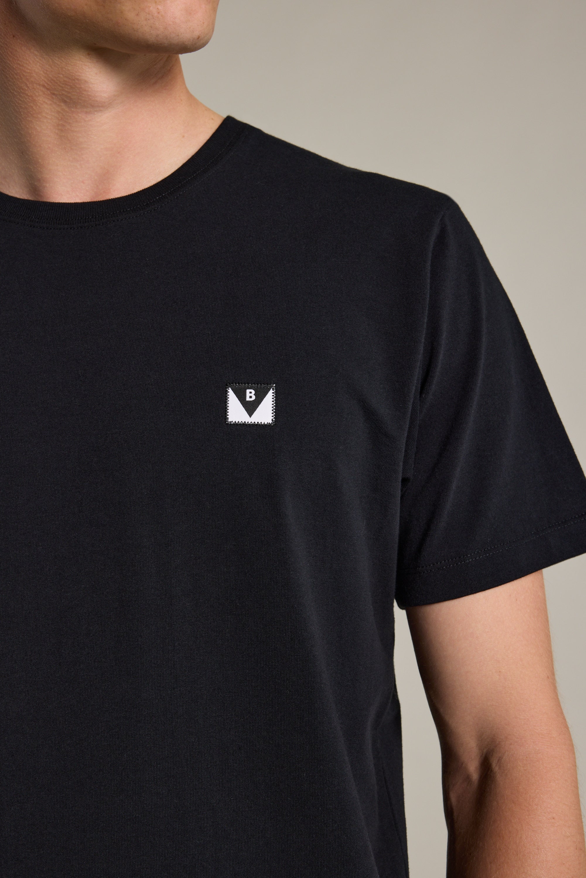 A person wears a Barkers Newton Washed Tee—an oversized, box-fit black t-shirt with a small ‘B’ patch on the left chest. The person's face is partially out of frame.