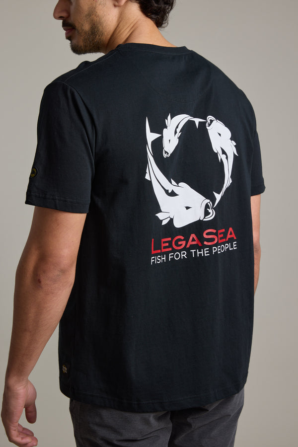 A man wears the Legasea Brand Tee by Legasea, crafted from organic cotton with white fish graphics in a circle and "LEGA SEA FISH FOR THE PEOPLE" on the back, supporting marine conservation in New Zealand.