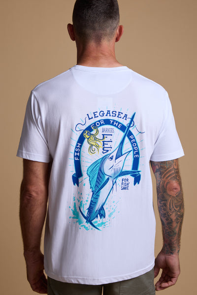 A man with short hair and a tattooed arm wears the Legasea Marlin Print t-shirt by Legasea, featuring a blue marlin, octopus, and the text: “LEGASEA FOR THE FISH, FOR THE PEOPLE, FOR FISH SAKE,” inspired by New Zealand's coast.