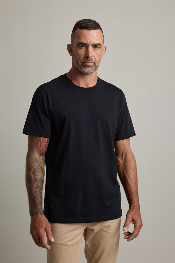 Man with tattoos wearing a Barkers Good Earth Cotton Essential Tee and beige pants.