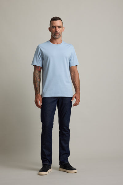 Man in a light blue Barkers Good Earth Cotton Essential Tee and dark jeans on a plain background.
