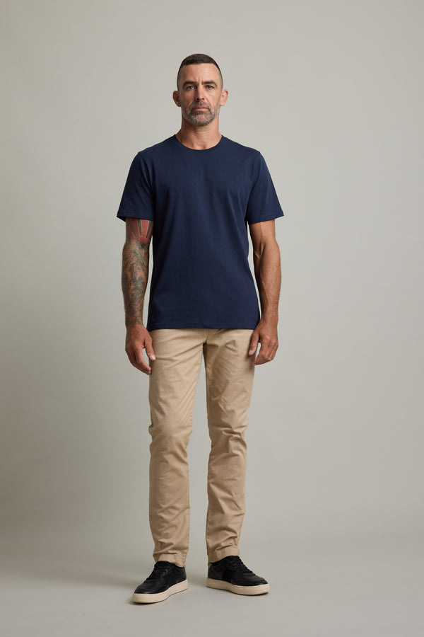 Man in a navy Barkers Good Earth Cotton Essential Tee and beige pants.