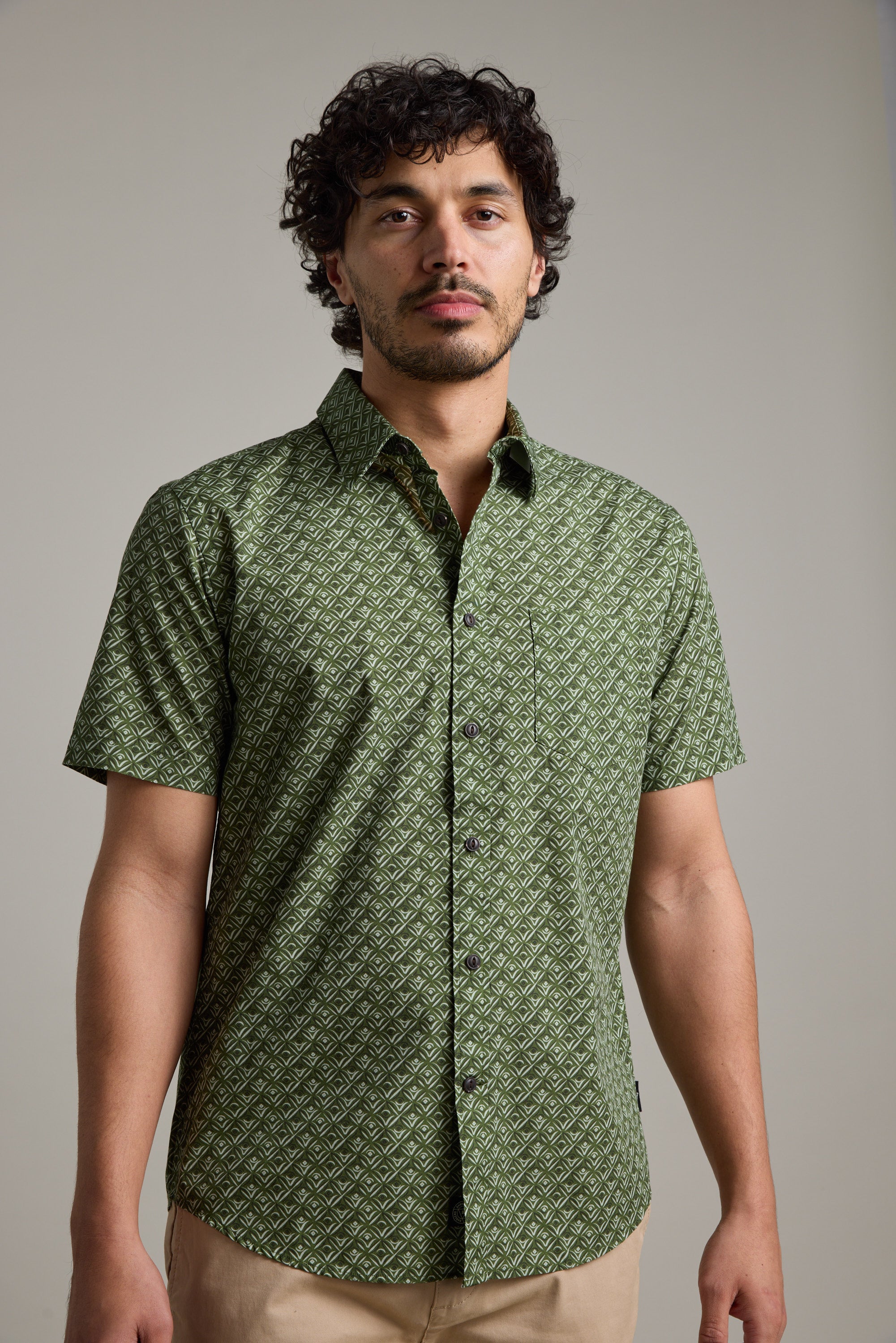 A man with curly dark hair and a short beard wears the Barkers Oxnard Print Shirt in green and beige pants, standing against a plain light background.