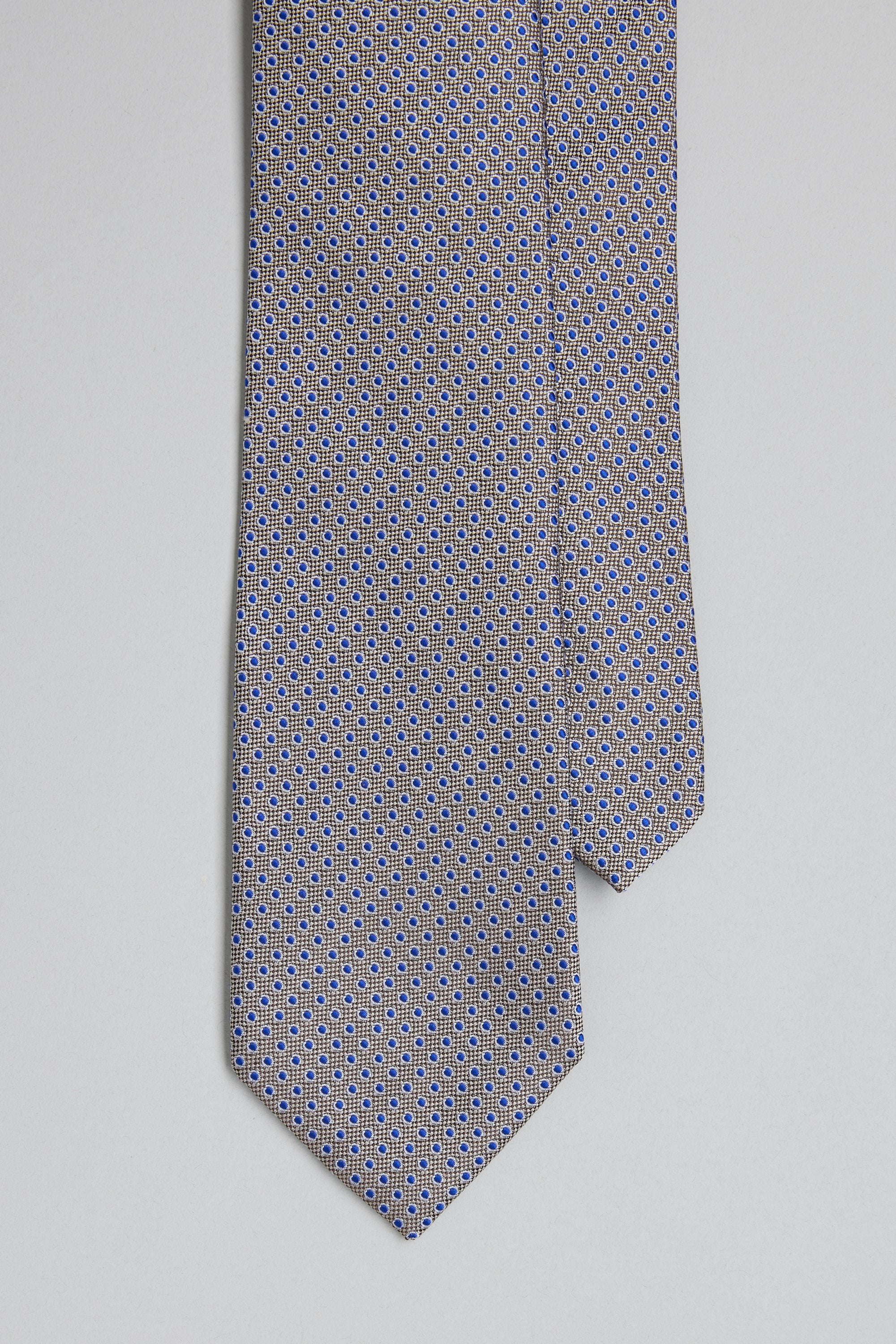 The Barkers Waller Dot Tie features a close-up of its silk fabric, adorned with a small blue and yellow jacquard geometric print on a light gray background, displayed on a plain white surface.
