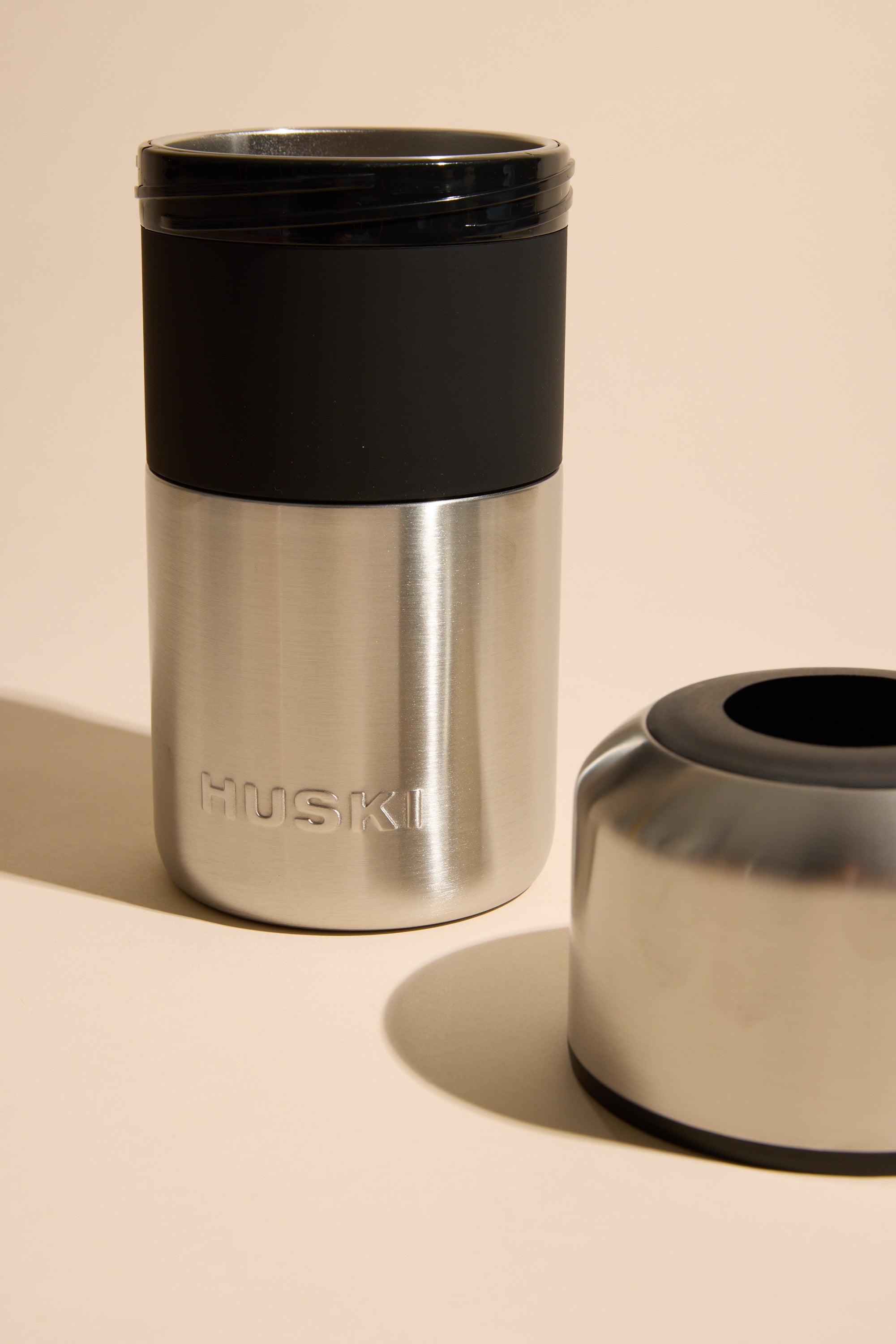 The Huski Wine Cooler by Huski is a stainless steel insulated cup with a black lid and detachable base, designed to keep wine cold for hours—ideal for enjoying your favorite drink anywhere.